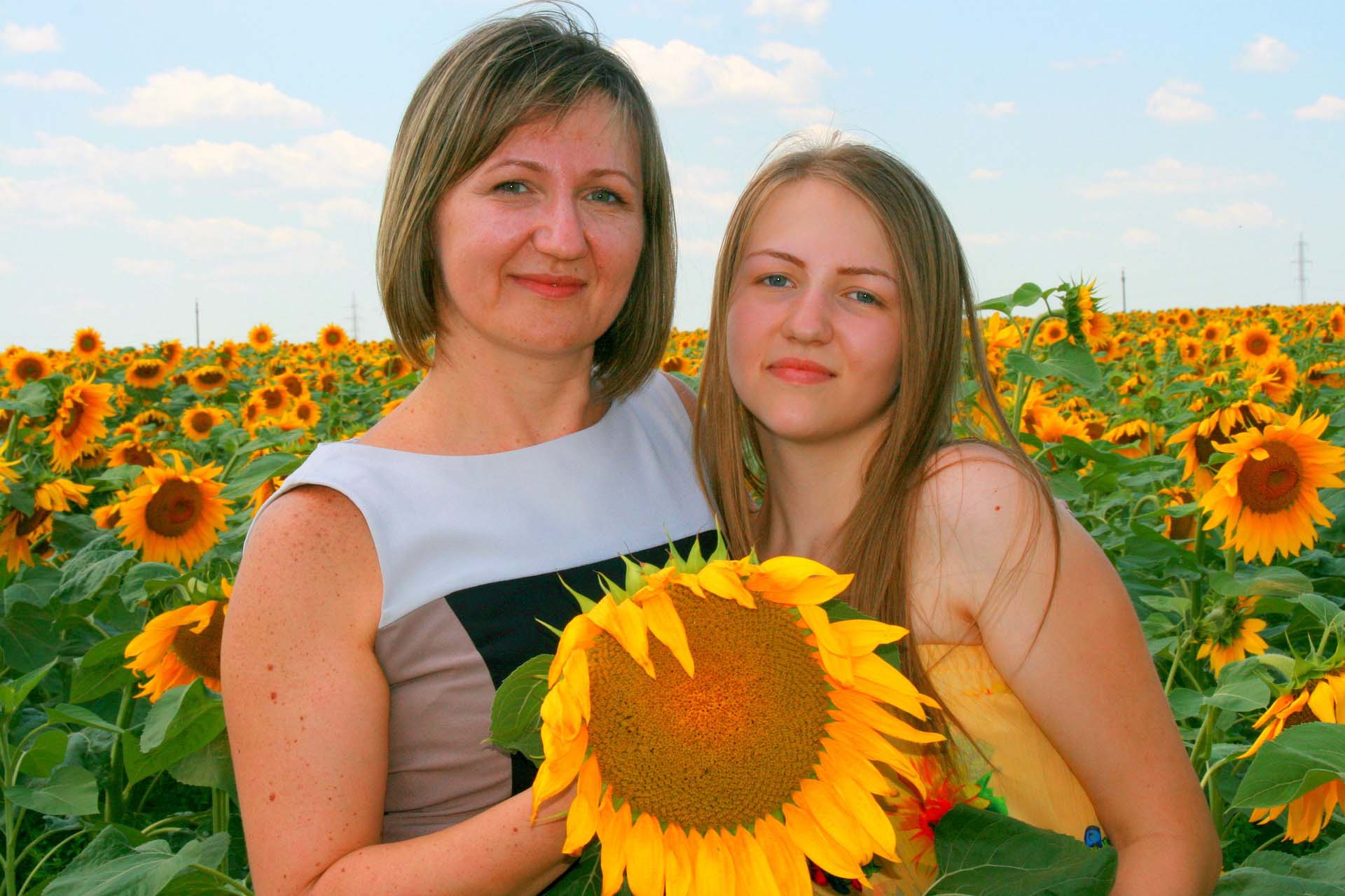 mom and daughter in sunflower field.