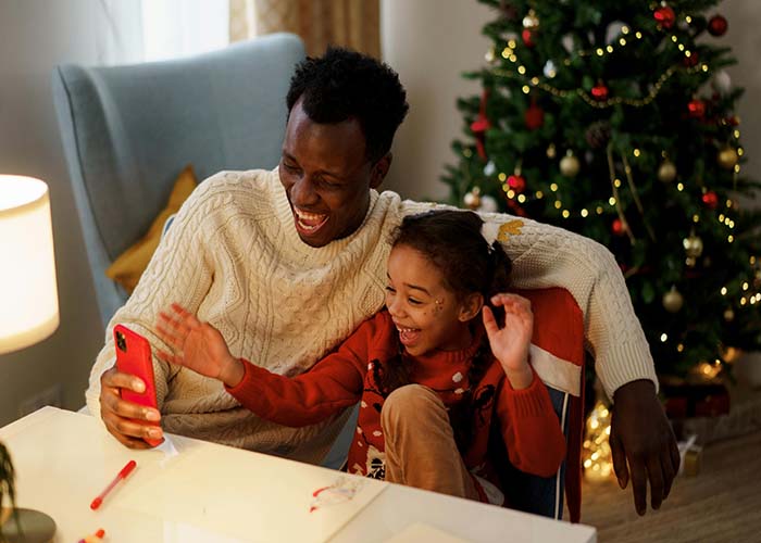 balance self-care holidays  Father and daughter laughing together sitting at a desk looking at a phone